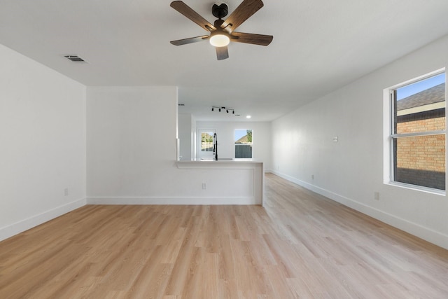 unfurnished room featuring plenty of natural light, visible vents, light wood-style flooring, and baseboards