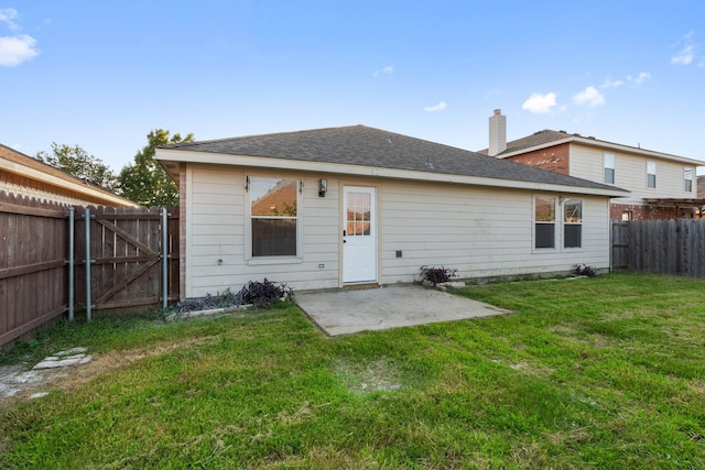 rear view of property featuring a lawn, a patio area, a fenced backyard, and a gate