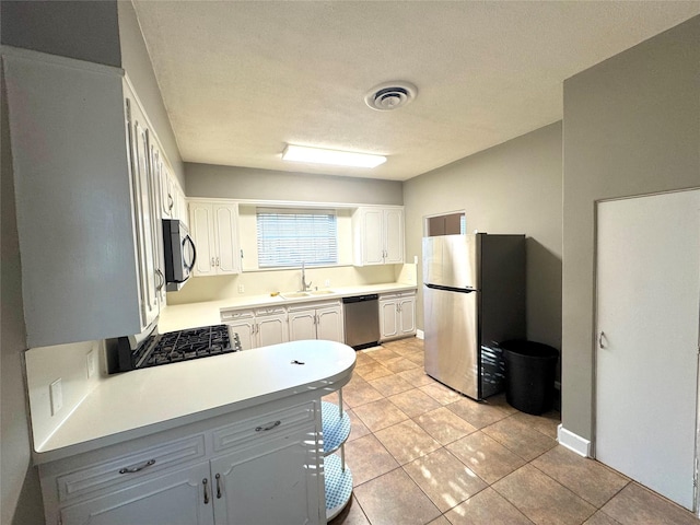 kitchen with visible vents, appliances with stainless steel finishes, light countertops, white cabinetry, and a sink