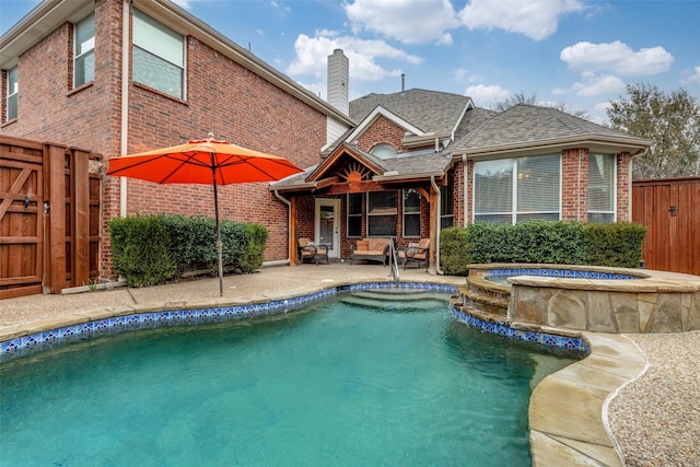 rear view of property with brick siding, a shingled roof, fence, a chimney, and a patio area