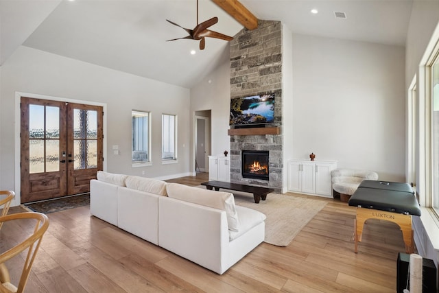 living area featuring high vaulted ceiling, a stone fireplace, wood finished floors, and beam ceiling