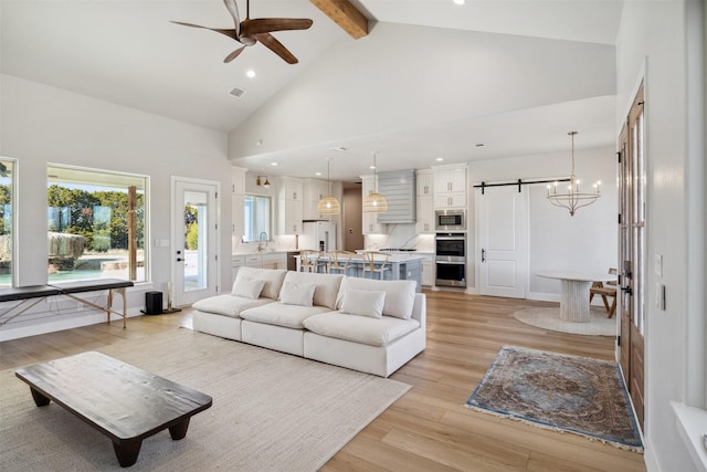 living room featuring light wood finished floors, visible vents, a barn door, high vaulted ceiling, and beamed ceiling