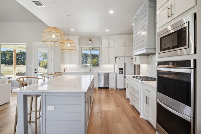 kitchen with visible vents, backsplash, appliances with stainless steel finishes, light wood-type flooring, and a kitchen bar