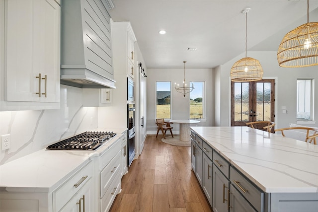 kitchen with light wood-style flooring, stainless steel appliances, custom exhaust hood, gray cabinets, and a center island