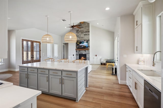 kitchen featuring french doors, gray cabinetry, stainless steel dishwasher, open floor plan, and a sink