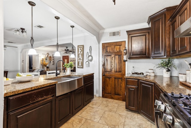 kitchen featuring stainless steel gas stove, decorative light fixtures, a sink, and dark brown cabinetry