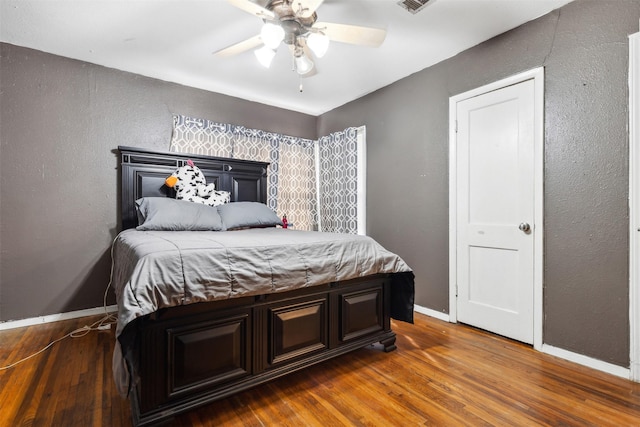 bedroom featuring visible vents, baseboards, a textured wall, ceiling fan, and dark wood-type flooring