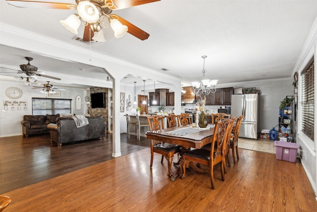 dining room with ornamental molding, arched walkways, a notable chandelier, and wood finished floors