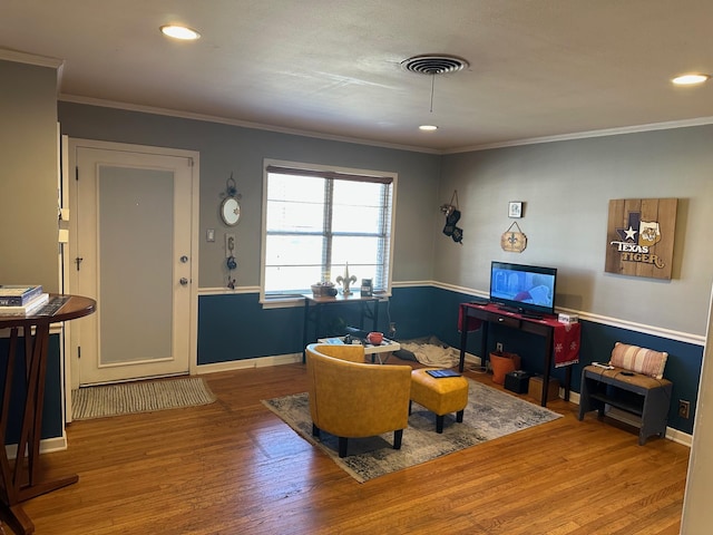 living area featuring baseboards, crown molding, visible vents, and wood finished floors