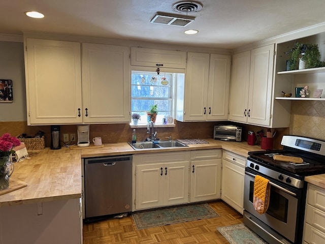 kitchen featuring stainless steel appliances, a sink, visible vents, white cabinets, and open shelves