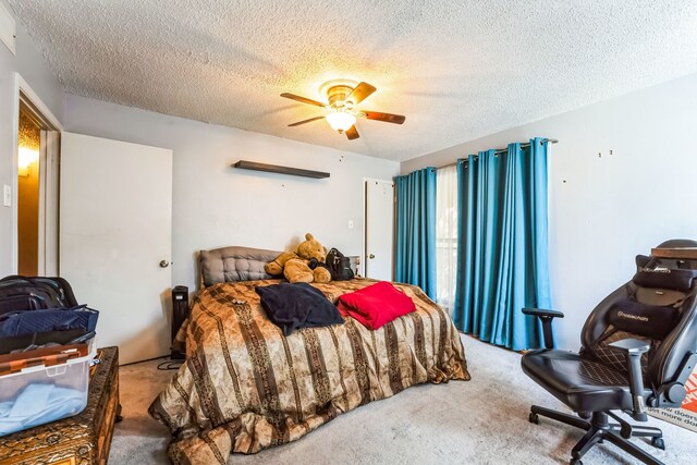 carpeted bedroom featuring ceiling fan and a textured ceiling