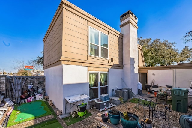 back of property featuring a patio area, a chimney, fence, and stucco siding