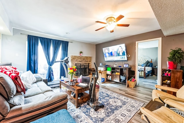 living room featuring a ceiling fan, a brick fireplace, and wood finished floors