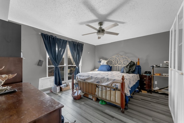 bedroom featuring a textured ceiling, a ceiling fan, and wood finished floors