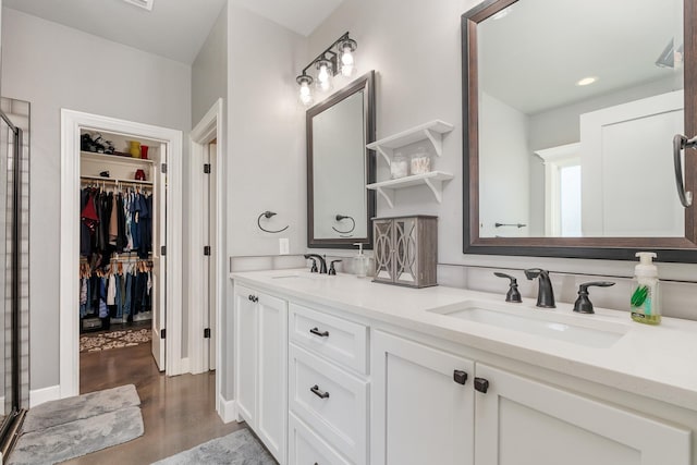 full bathroom with double vanity, wood finished floors, a sink, and a walk in closet