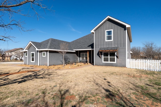 view of front facade featuring a shingled roof, fence, and board and batten siding