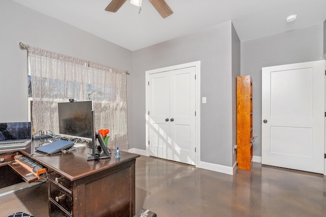 home office featuring concrete floors, a ceiling fan, and baseboards