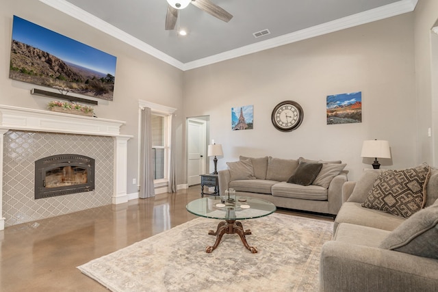 living room featuring visible vents, a tiled fireplace, ceiling fan, ornamental molding, and a high ceiling