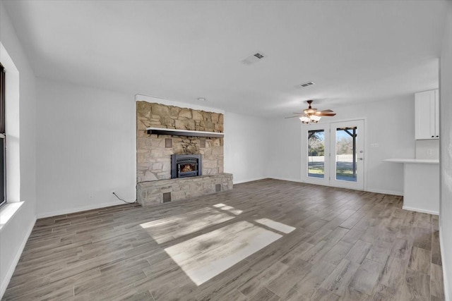 unfurnished living room with light wood-type flooring, a fireplace, and visible vents