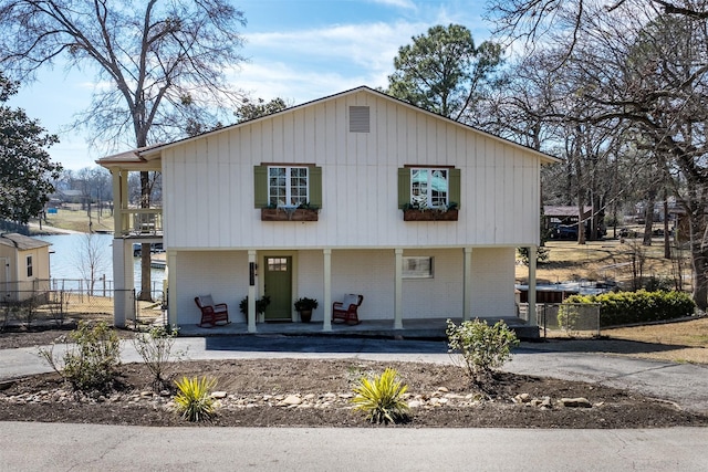 view of front of home with covered porch, brick siding, and fence