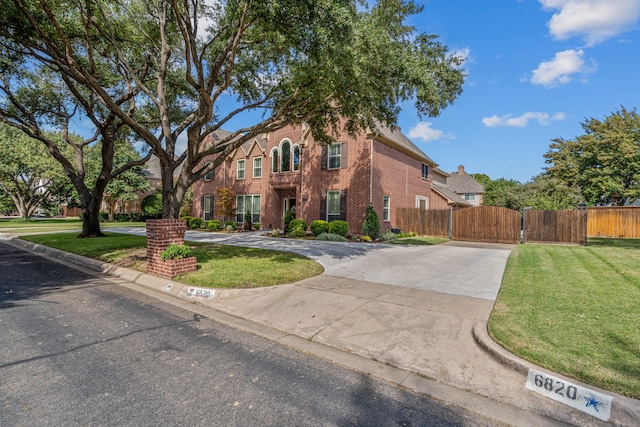 view of front of property with brick siding, fence, concrete driveway, and a front yard