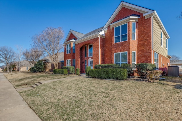 traditional-style house featuring a front yard, brick siding, and central AC