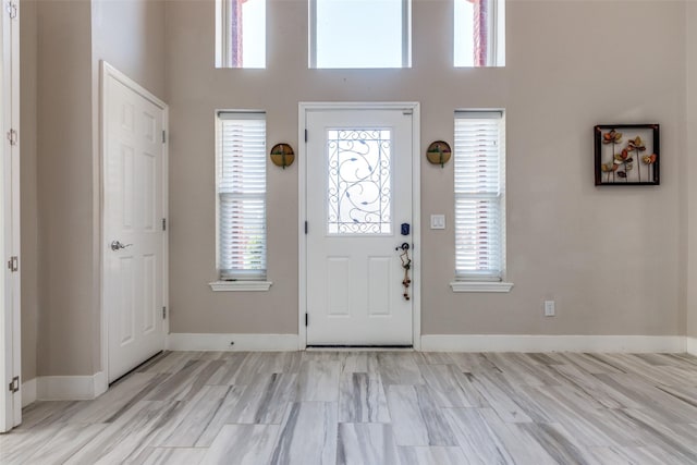 foyer featuring a wealth of natural light, a high ceiling, and baseboards