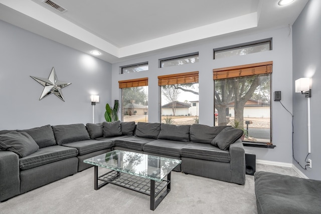 carpeted living area featuring a tray ceiling, recessed lighting, visible vents, and baseboards