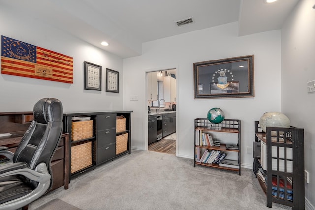 office space featuring recessed lighting, light carpet, a sink, visible vents, and baseboards