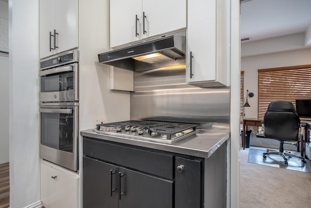 kitchen with stainless steel appliances, dark cabinetry, white cabinets, and under cabinet range hood