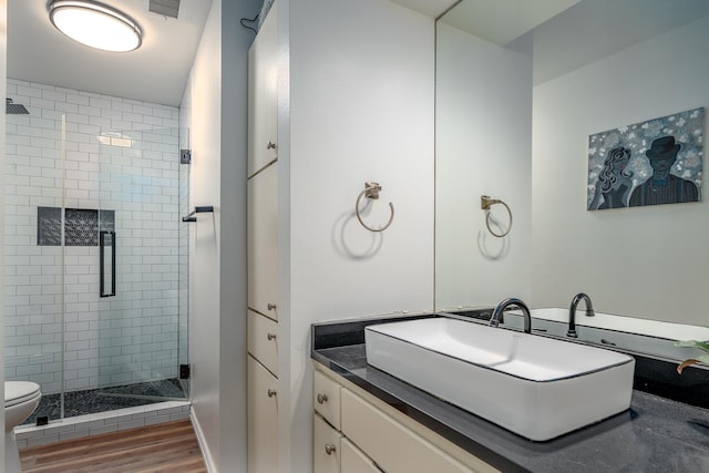 bathroom featuring visible vents, toilet, wood finished floors, vanity, and a shower stall