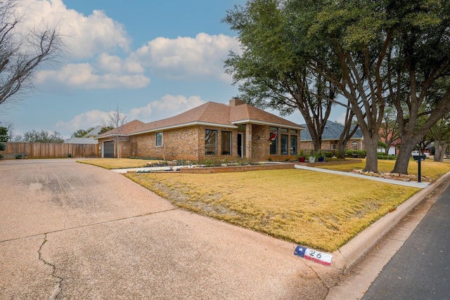 view of front of house with brick siding, concrete driveway, an attached garage, a front yard, and fence