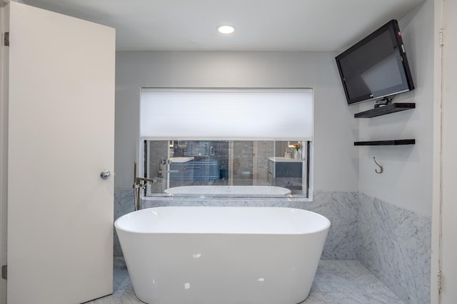 full bathroom with a freestanding tub, wainscoting, tile walls, and marble finish floor