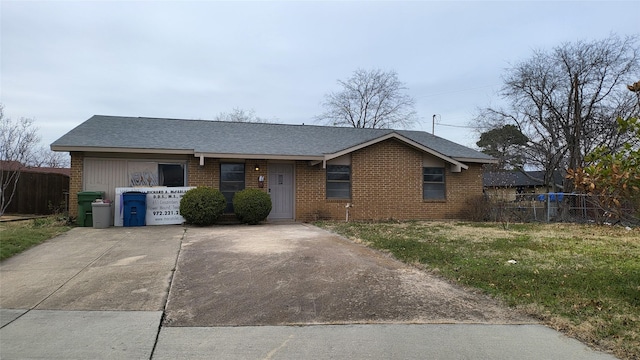 ranch-style house featuring brick siding, a front lawn, a shingled roof, and fence