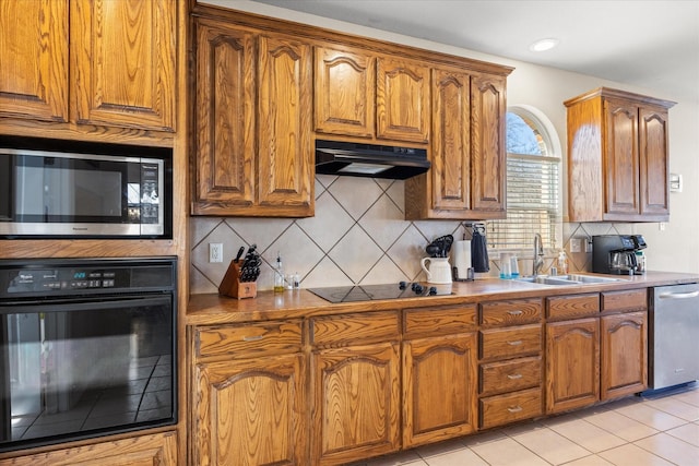 kitchen featuring black appliances, brown cabinets, a sink, and under cabinet range hood