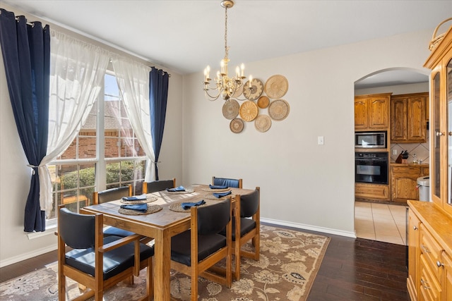 dining room with arched walkways, dark wood-style flooring, baseboards, and an inviting chandelier