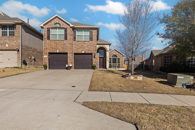 traditional-style house featuring driveway, a front yard, a garage, and brick siding