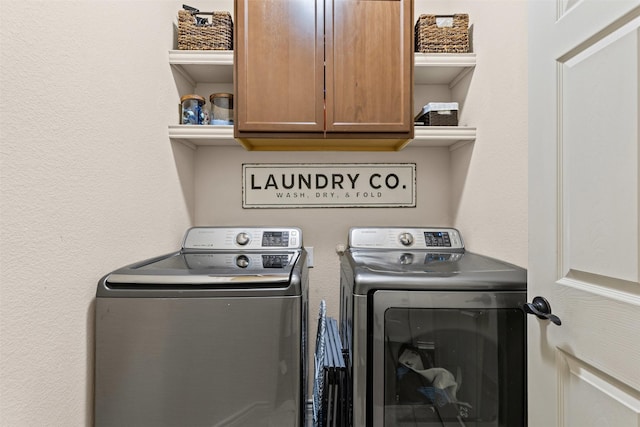 laundry area with cabinet space, separate washer and dryer, and a textured wall