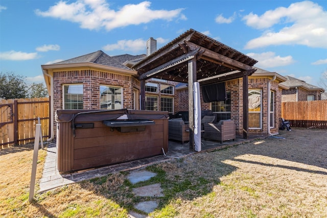 rear view of property featuring brick siding, a chimney, a fenced backyard, and a hot tub