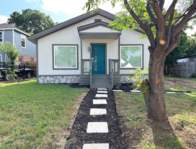 view of front of house featuring entry steps, a front lawn, and fence