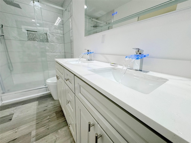 full bathroom with double vanity, wood finished floors, a sink, and toilet