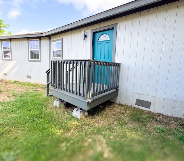 entrance to property featuring a yard, crawl space, a wooden deck, and visible vents