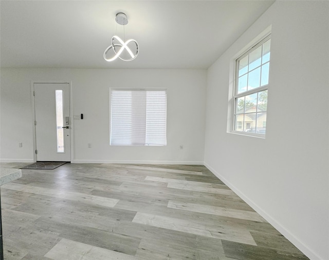 interior space with light wood-style floors, a chandelier, and baseboards