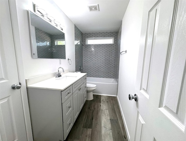 bathroom with shower / tub combination, toilet, wood finished floors, vanity, and visible vents