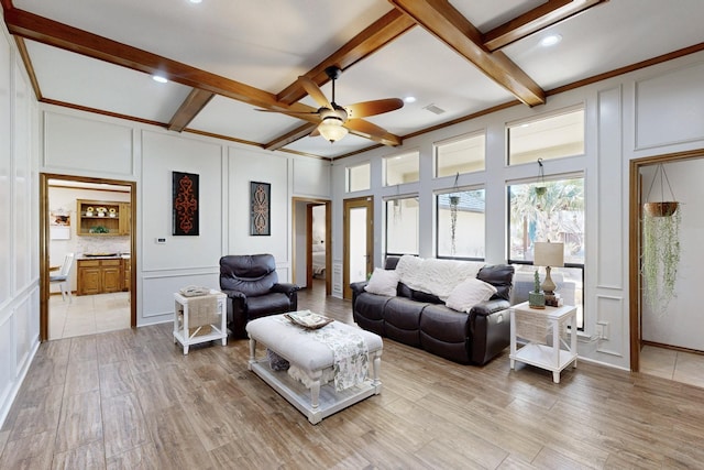 living room with light wood-type flooring, a decorative wall, and beamed ceiling