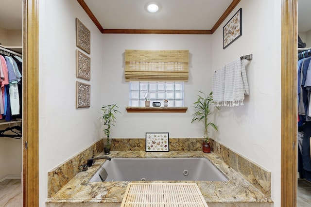 bathroom featuring a spacious closet, a tub with jets, and crown molding