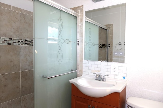 bathroom featuring toilet, vanity, tile walls, tasteful backsplash, and a stall shower