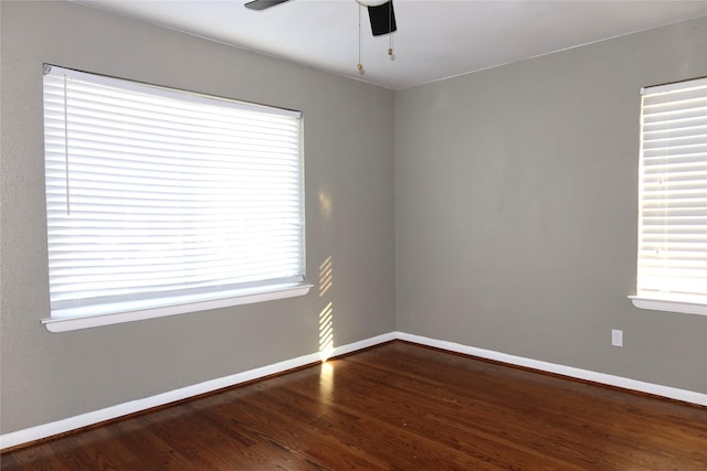 spare room featuring a ceiling fan, plenty of natural light, baseboards, and wood finished floors