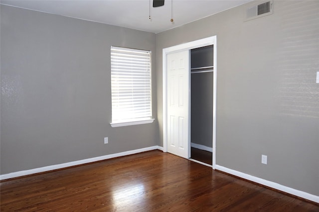 unfurnished bedroom with a closet, visible vents, ceiling fan, wood finished floors, and baseboards