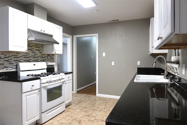 kitchen with tasteful backsplash, dark countertops, white gas stove, under cabinet range hood, and a sink